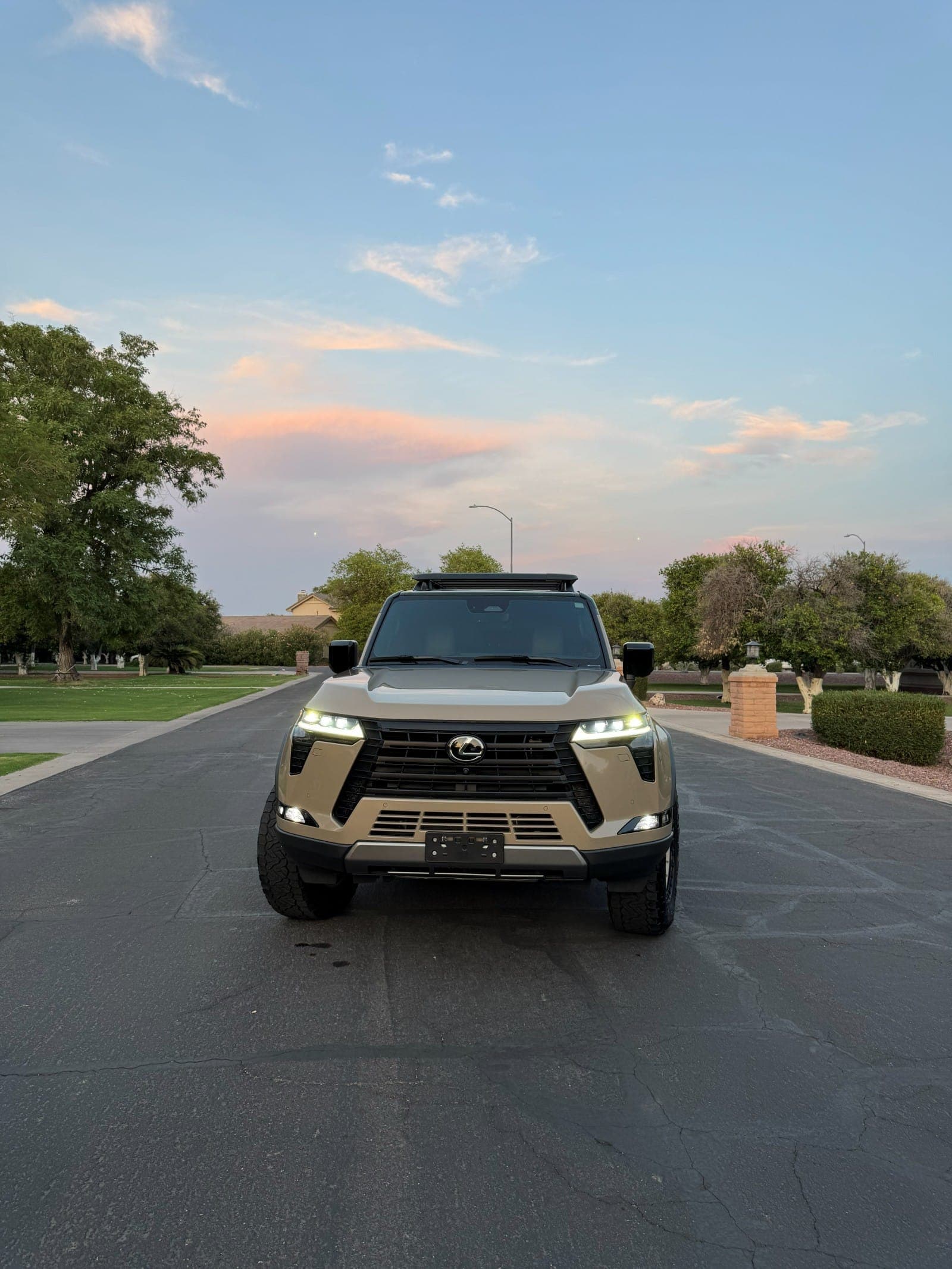 Head-on view of a detailed Lexus GX at dusk, headlights on